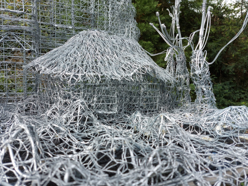 A detail of a sculpture by Carl Gabriel, of a plantation house set against the facade of the old Hall